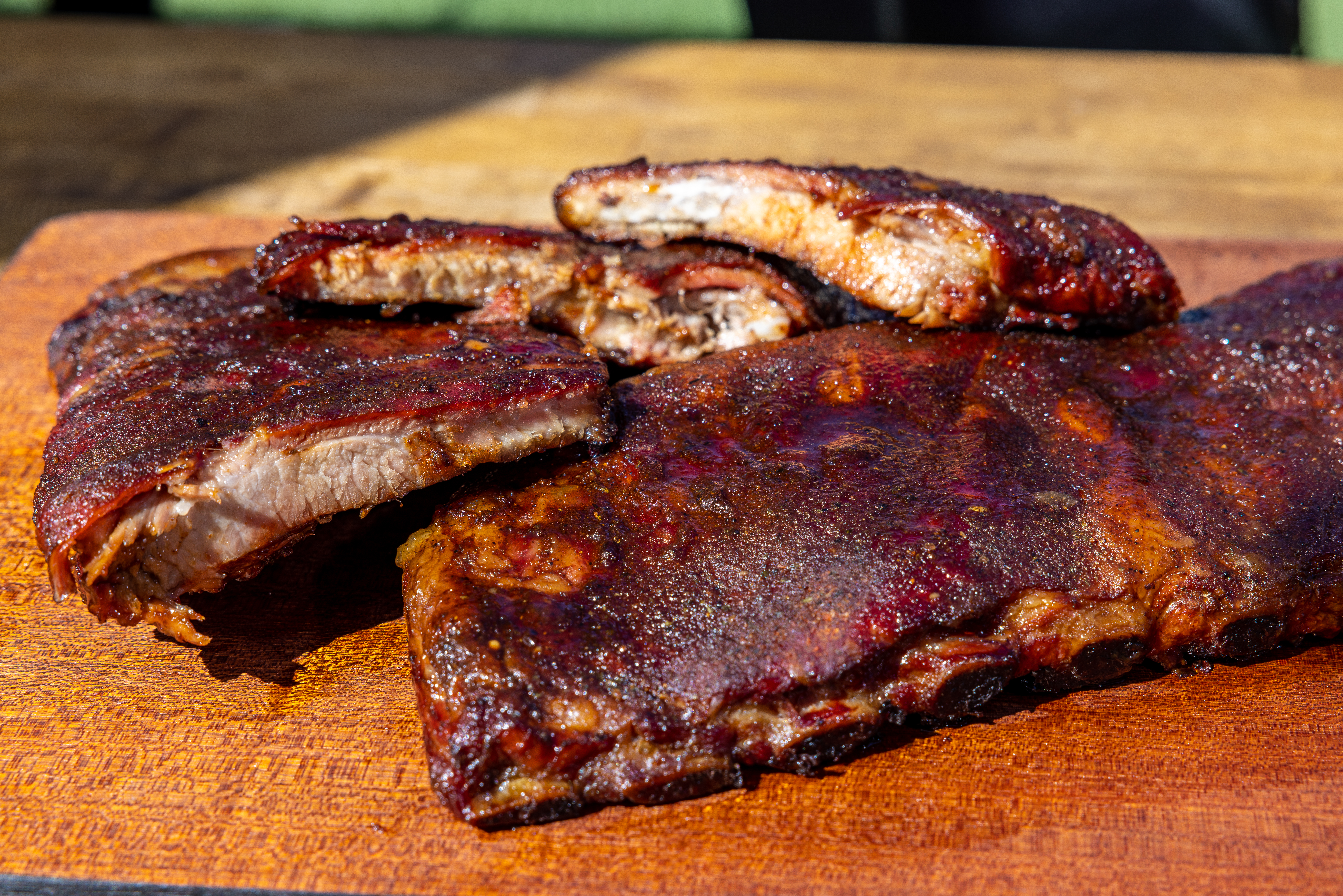 Up close of partially separated, cooked ribs on wood board